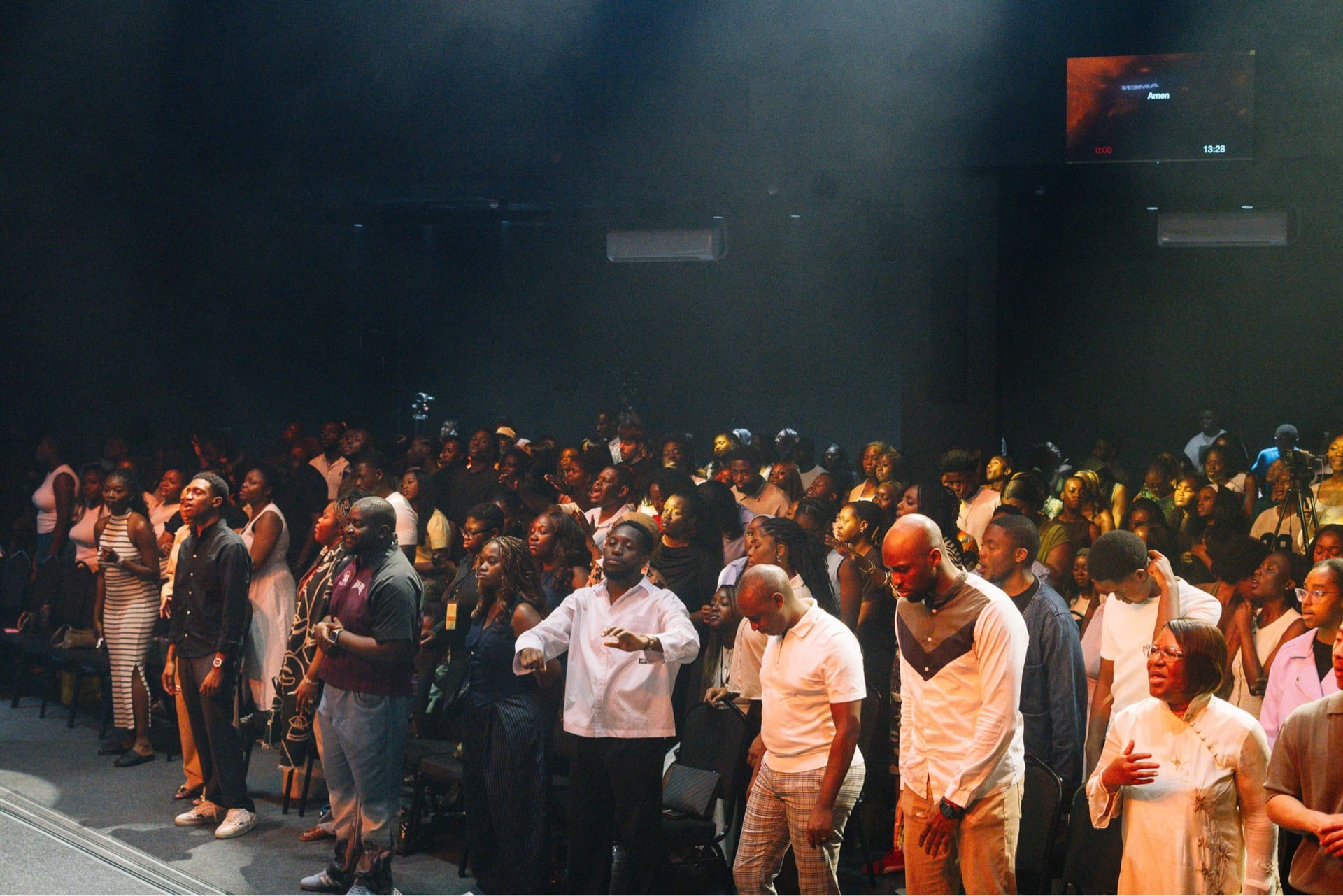 The congregation standing together in worship at a Sunday gathering